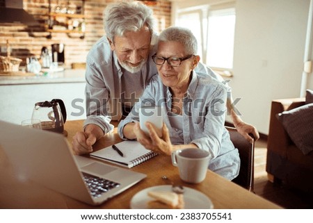 Senior couple using a smartphone together at home Royalty-Free Stock Photo #2383705541