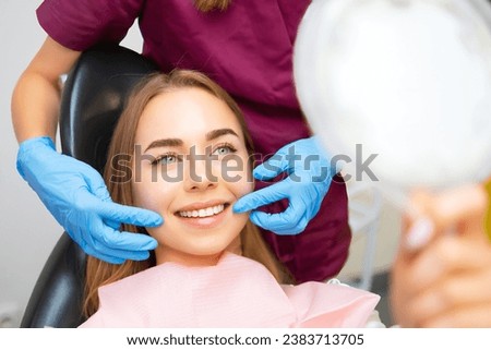 Dentist demonstrates the perfect smile of the patient after implatation of dental veneers or teeth whitening.  Royalty-Free Stock Photo #2383713705