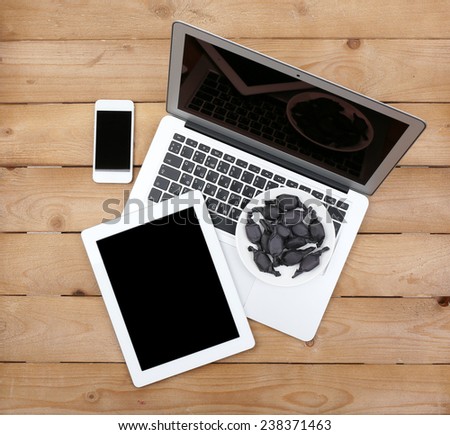 Open notebook, digital tablet and smart phone with saucer of candies on wooden background, top view