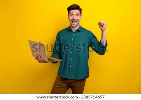 Photo of cheerful positive good mood man wear trendy clothes raise hand fist celebrate success isolated on yellow color background