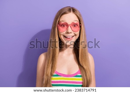 Photo portrait of lovely teen blonde lady heart glasses amazed smile wear trendy striped garment isolated on purple color background