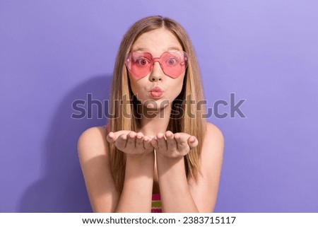 Photo portrait of lovely teen blonde lady heart glasses send air kiss wear trendy striped garment isolated on purple color background
