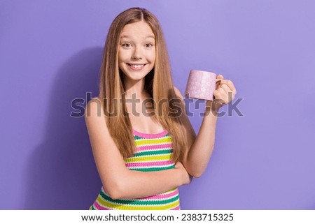 Portrait of cheerful friendly teen girl with long hairstyle wear colorful singlet holding cup of cacao isolated on purple background