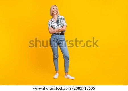 Full length photo of lovely girl dressed print blouse jeans hold arms folded look at promo empty space isolated on yellow color background