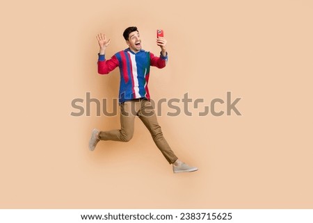 Full body size photo of crazy man jumping running to entertainment selfie shooting for fans account isolated on beige color background