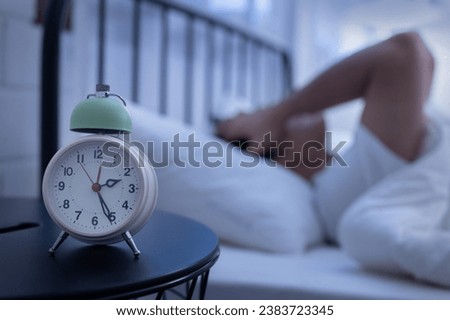 Asian man suffer from insomnia on his bed with a clock on bed side Royalty-Free Stock Photo #2383723345