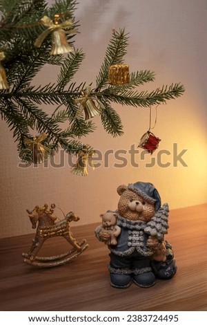 Decorative figurine of antique golden rocking horse and a bear with a Christmas tree, under fir tree. Festive new year decor, warm composition
