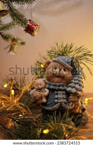 Decorative figurine of a bear with a Christmas tree, decorated with a pine tree and Christmas lights. Festive new year decor, warm composition