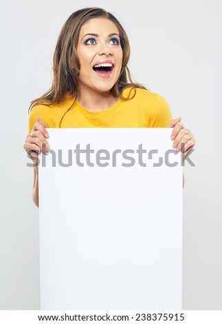 smiling woman holding sign card looking up. studio isolated portrait of beautiful girl.