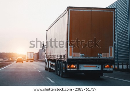Modern white semi-trailer trucks on the highway driving in the right lane. Commercial vehicle for shipping and post delivery. Shipping of the goods on land with a door-to-door delivery process. Royalty-Free Stock Photo #2383761739