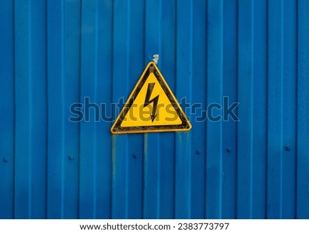 electrical hazard warning sign located on an old fence.