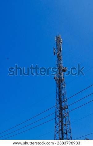 Industrial Photography. A towering radio signal tower against a bright blue sky background. Technology, radio signal flow, signal towers, signal distribution, transmission towers