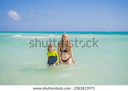 A radiant pregnant mother and her excited son share a tender moment on a serene, snow-white beach, celebrating family love amidst nature's beauty