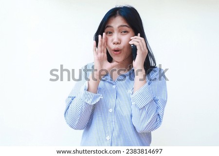 excited asian woman wearing striped shirt using smartphone screaming isolated on white background