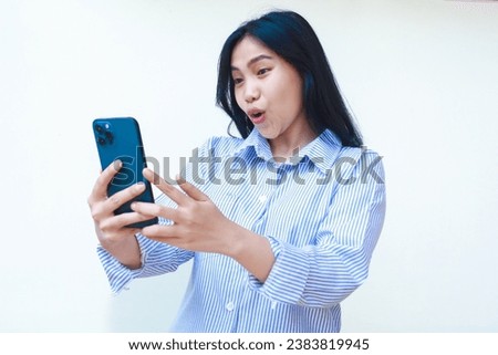 happy asian woman using mobile phone shocked surfing in social media wearing striped shirt isolated on white background