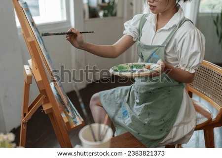 Young female student studying in the art studio Learn how to draw landscapes Mixing watercolors to create art on cardboard design on canvas Develop your art drawing skills with hobby studio activities