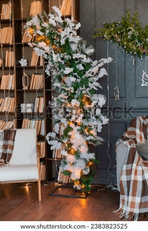 Christmas office with bookshelves with a sofa, Christmas tree with toys. Interior decoration for the holiday. present. Home comfort