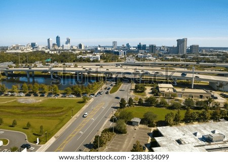 Aerial view of Jacksonville city with high office buildings and american freeway intersection with fast driving cars and trucks. View from above of USA transportation infrastructure