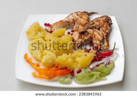 A plate of grilled fish decorated with Mashed potato and vegetables