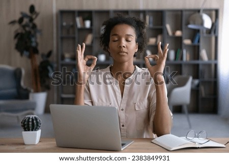 Peaceful African remote employee, student girl, business woman practicing concentration and mindfulness, meditating and relaxing at home office workplace, relaxing on break, making zen hand gesture