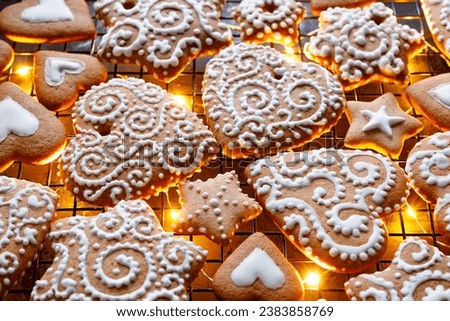 Christmas gingerbreads in the shapes of hearts and stars decorated with white icing, focus on the gingerbread cookie inside. Homemade, hand-decorated gingerbread cookies. Royalty-Free Stock Photo #2383858769