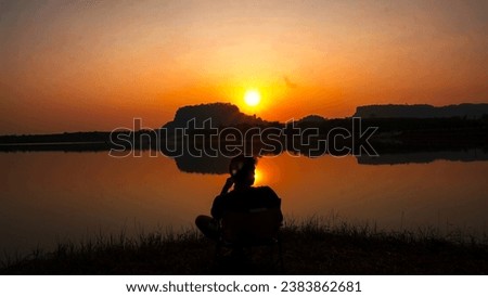 A man admiring lake sunset. Relaxing on outdoor chair .