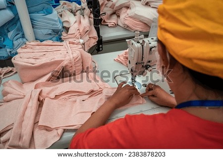 Female worker working in a garment factory in an industrial park in Ho Chi Minh City, Vietnam, with modern machinery and technology systems. Royalty-Free Stock Photo #2383878203