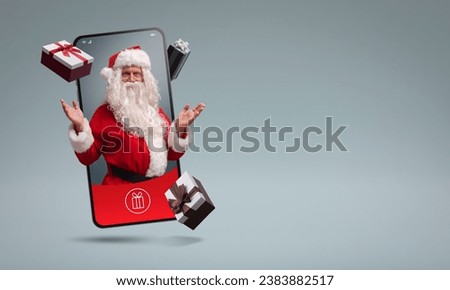Santa Claus in a smartphone screen and Christmas gifts, online shopping app concept