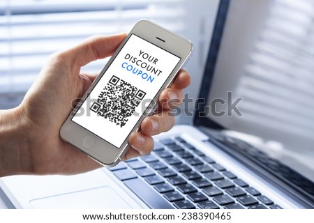 Discount coupon with QR code on smartphone with laptop in background Royalty-Free Stock Photo #238390465