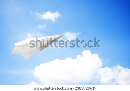 White paper plane flying on the air on the sky background.  Paper plane flying symbol of freedom and peace.