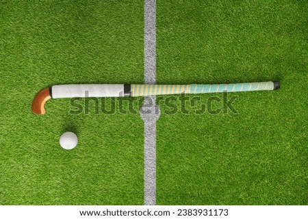 Hockey, ball and stick on green field, pitch and equipment against grass background. Sports equipment, top view and astroturf with in practice, training and sport. Royalty-Free Stock Photo #2383931173