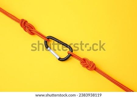 One metal carabiner with ropes on yellow background, top view Royalty-Free Stock Photo #2383938119