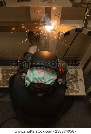 NEWPORT NEWS, Va. (Sept. 17, 2019) Fireman Lidia Luna, from Houston, assigned to USS Gerald R. Ford's (CVN 78) engineering department, stick welds in Ford's machine shop.  Royalty-Free Stock Photo #2383949587