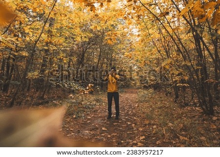 Hiker aged 25 takes a selfie with a colourful autumn forest in the Hoge Kempen National Park in eastern Belgium. Wilderness in Flanders in November.