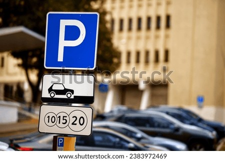 Paid parking sign. Post with parking signs. Parked cars on background. Crowded parking