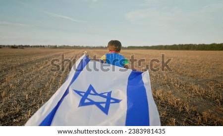 Happy Israeli Jewish little cute boy running with Israel national flag. Independence Day. Patriotism. High quality photo Royalty-Free Stock Photo #2383981435