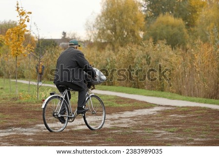 A man rides a bicycle on a path among autumn nature. Activity in a healthy lifestyle. Contemporary ecological transport in the countryside