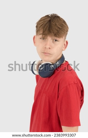 Caucasian 15 year old teenage boy, wearing a red t-shirt,  with headphones loose around his neck