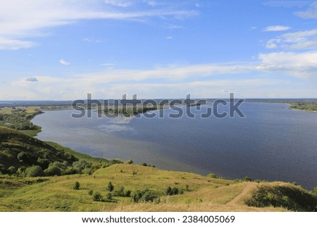 Summer Volga landscape from Bird's Flight mountain - the highest point of Chuvashia: soft green slopes of the banks of the Volga, the horizon line and a bright blue sky.