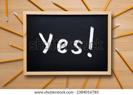 Yes Word on a school board. Yes concept. Text written with white chalk on a blackboard on background with pencils. Choice, definition, school, business, study. Royalty-Free Stock Photo #2384016785