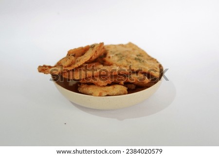 Isolated picture of delicious Tempeh Goreng or tempeh chips on white background taken from eye angel. Slices of tempeh coated with flour and spices then fried, crispy and crunchy. copy space for text