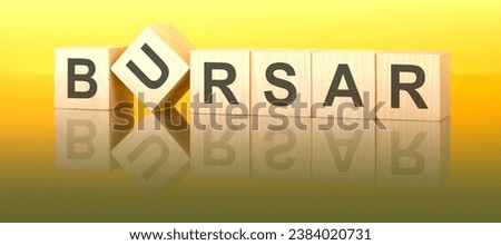bursar text on wooden cubes on a working table. light yellow background. reflection of an image on a glass surface concept.