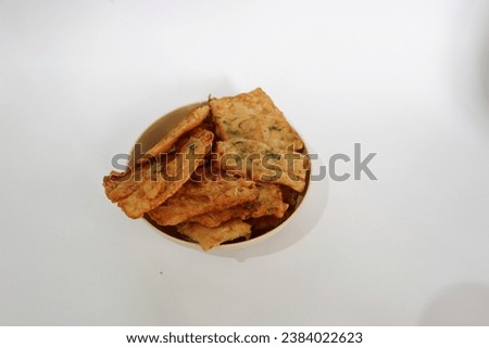 Isolated picture of delicious Tempeh Goreng or tempeh chips on white background taken from high angel. Slices of tempeh coated with flour and spices then fried, crispy and crunchy. copy space for text