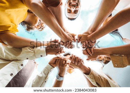 Multi ethnic group of young people holding hands outdoors - Community life style concept with guys and girls hugging together outside - Unity, support and collaboration concept Royalty-Free Stock Photo #2384043083