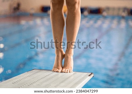 the feet of sportswoman athlete diver standing on a springboard in swimming pool Royalty-Free Stock Photo #2384047299