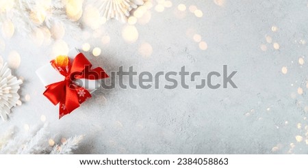 Merry Christmas and Happy Holidays greeting card, frame, banner. New Year. Noel. White Christmas red ribbon gift and ornaments on light background top view. Winter holiday xmas theme. Flat lay. Royalty-Free Stock Photo #2384058863
