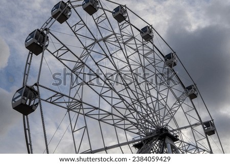 The Ferris wheel attraction is large against the background of a cloudy textured sky. Horizontal photo