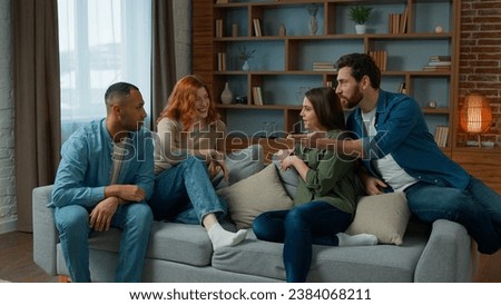 Ethnic friends sit on couch in living room diverse colleagues teammates women girls and men guys smiling talk discuss share plans friendly discussion dialogue laugh friendship weekend meeting at home Royalty-Free Stock Photo #2384068211