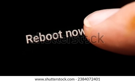 Man hand finger pressing the reboot now computer restart button on a touch screen display rebooting a smartphone, tablet mobile phone device, macro detail, closeup. Turning on and off concept, boot