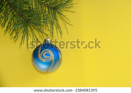 New Year's background with a fir branch, pine cone and decor on a yellow background.